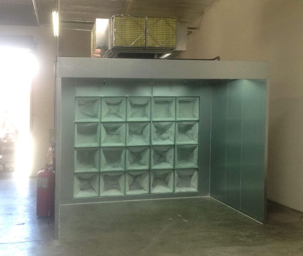 Industrial air filter system in a garage featuring a large square filter panel with multiple compartments, mounted under an air handling unit.