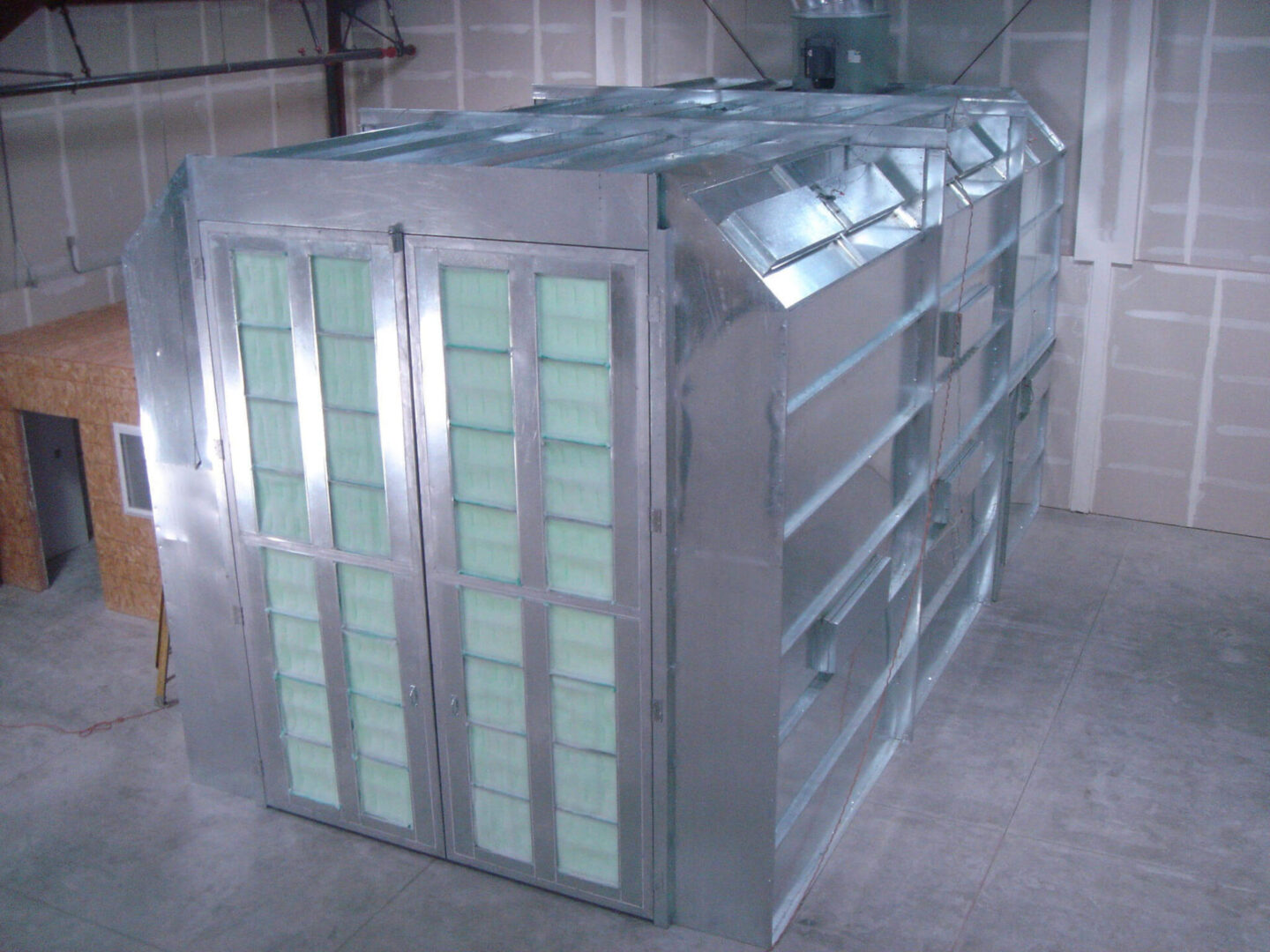 Large, metallic hvac duct system with multiple branches and green filters, installed in an industrial setting.