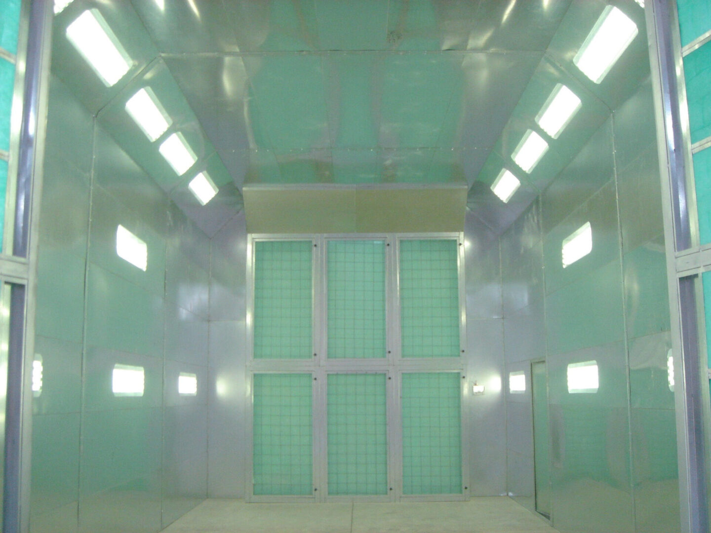 An empty, brightly lit room with mint green walls featuring large double doors and multiple small windows.