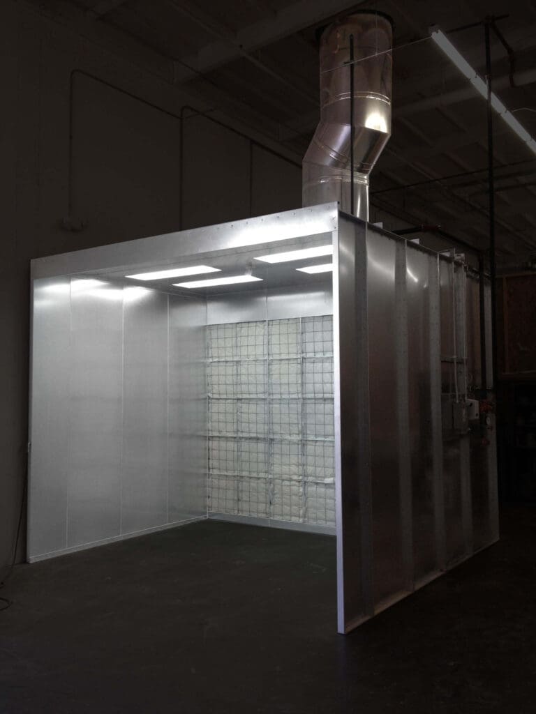 A large industrial cold storage room with transparent walls, filled with stacked boxes, illuminated by overhead lights in a warehouse setting.