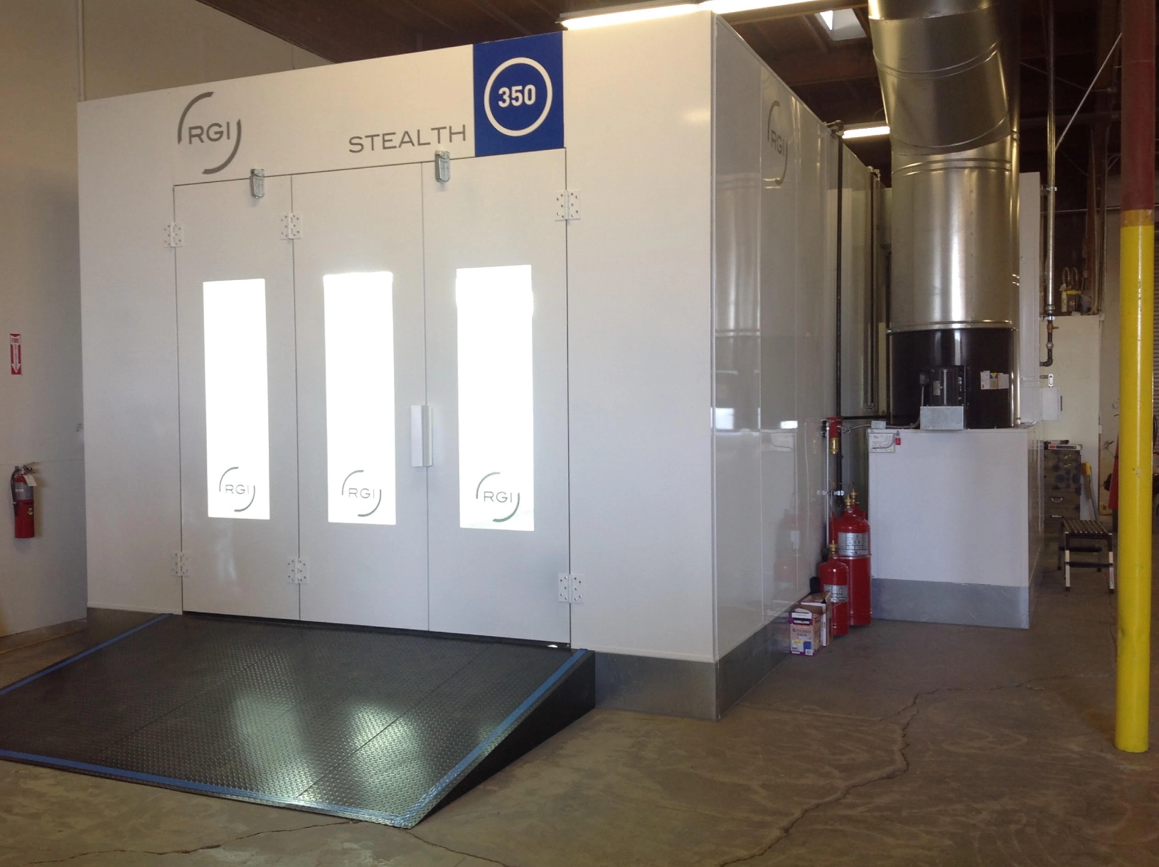 Large industrial powder coating oven with three doors, marked with the rgj logo, situated in a workshop environment.