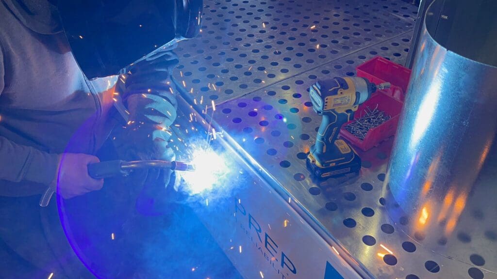 A person welding on top of a metal surface.